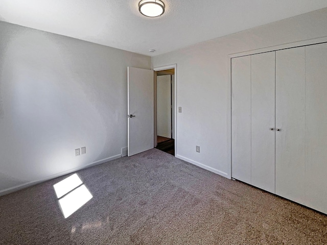unfurnished bedroom featuring carpet floors, baseboards, visible vents, and a closet