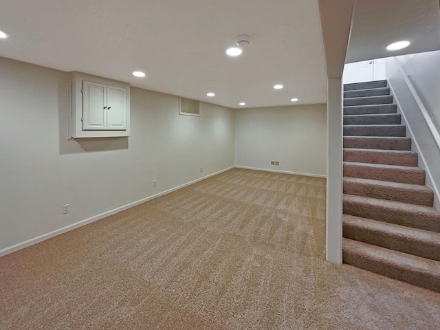 finished below grade area featuring baseboards, recessed lighting, stairs, and light carpet