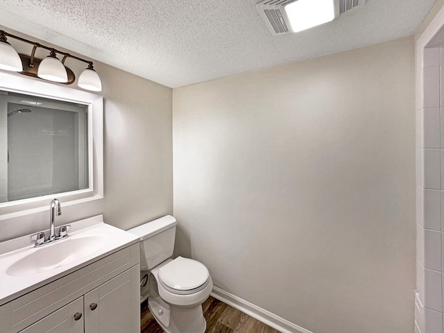 bathroom with vanity, wood finished floors, toilet, baseboards, and a textured ceiling
