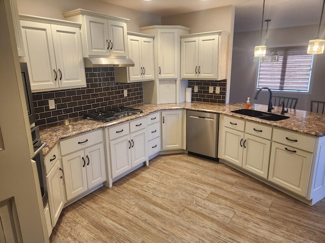 kitchen with a sink, a peninsula, under cabinet range hood, light wood-style floors, and stainless steel appliances