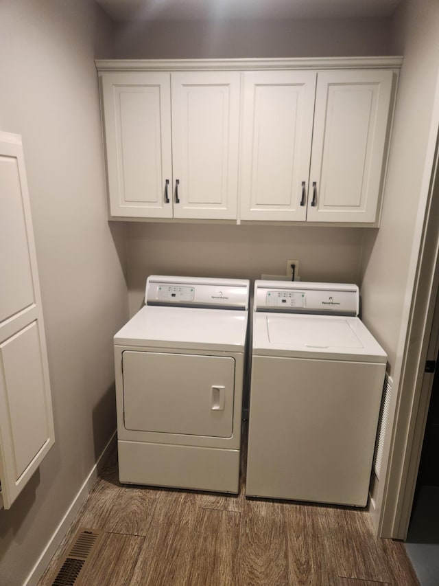 clothes washing area featuring cabinet space, separate washer and dryer, baseboards, and dark wood-type flooring