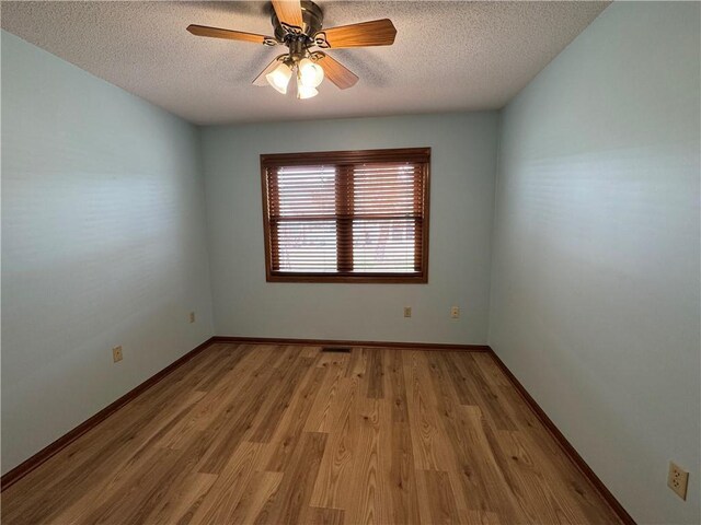 empty room featuring baseboards, a ceiling fan, a textured ceiling, and wood finished floors