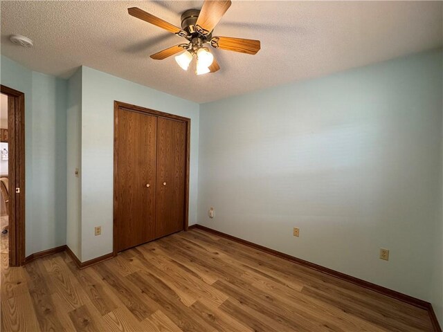 unfurnished bedroom featuring a ceiling fan, a textured ceiling, light wood-type flooring, baseboards, and a closet