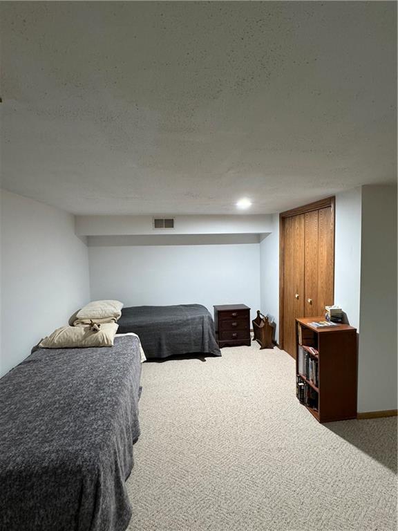 carpeted bedroom featuring a textured ceiling and visible vents