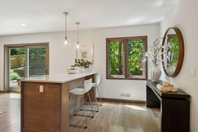 7000 Lanham Ln, Edina, MN 55439 - kitchen with wood finished floors, a kitchen breakfast bar, hanging light fixtures, a peninsula, and recessed lighting