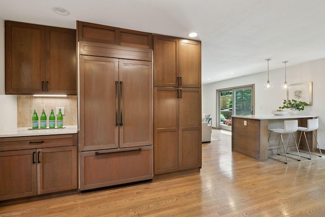 7000 Lanham Ln, Edina, MN 55439 - kitchen featuring paneled fridge, light countertops, pendant lighting, light wood-style flooring, and decorative backsplash