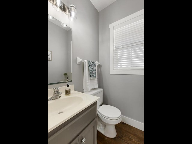 bathroom featuring toilet, baseboards, wood finished floors, and vanity