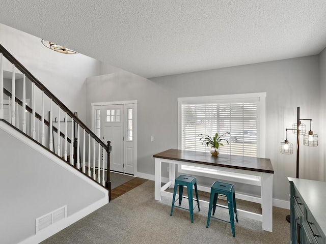 foyer featuring carpet floors, a textured ceiling, baseboards, and stairway