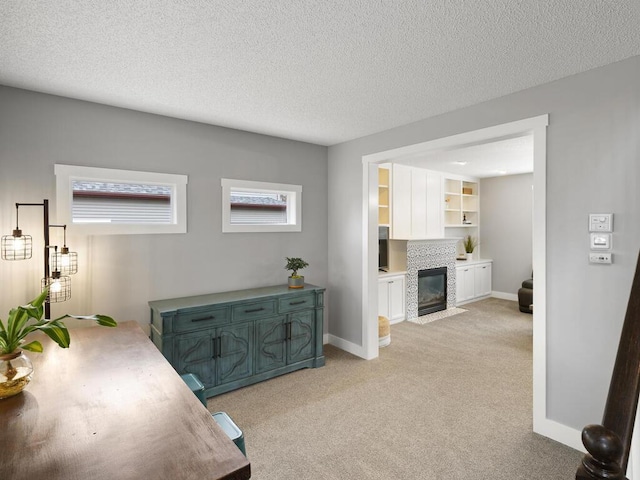 hallway with a textured ceiling, light colored carpet, and baseboards