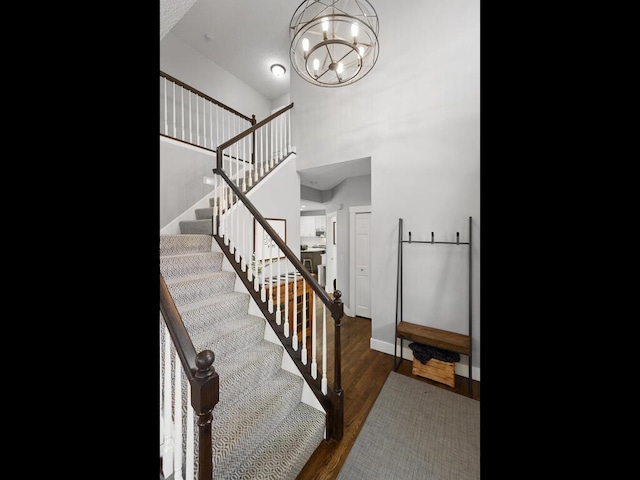 stairs featuring baseboards, an inviting chandelier, and wood finished floors