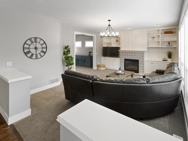 carpeted living room with a chandelier, baseboards, visible vents, and a tile fireplace