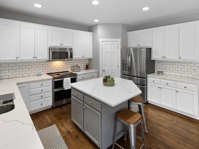kitchen featuring gray cabinetry, appliances with stainless steel finishes, tasteful backsplash, and light stone counters