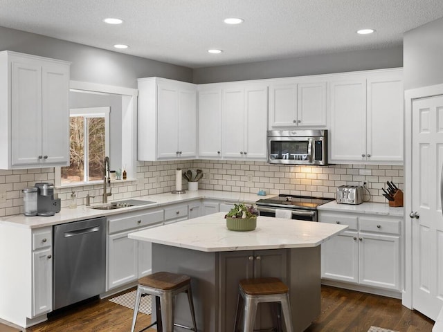 kitchen featuring a breakfast bar area, dark wood-style flooring, a sink, stainless steel appliances, and white cabinetry