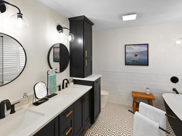 bathroom with double vanity, tile walls, wainscoting, and a sink