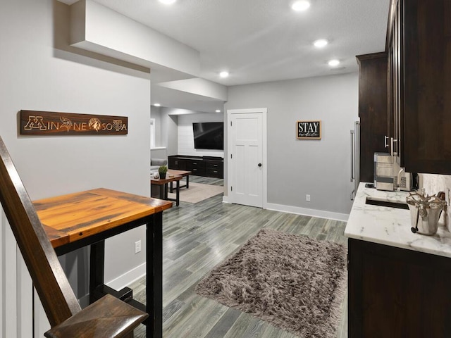 interior space featuring dark brown cabinets, baseboards, recessed lighting, and wood finished floors