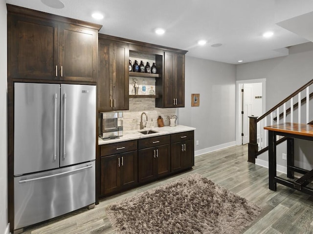 bar featuring light wood-type flooring, decorative backsplash, baseboards, and high quality fridge