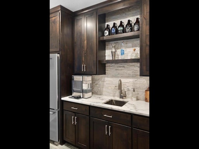 bar featuring a sink, tasteful backsplash, freestanding refrigerator, and indoor wet bar