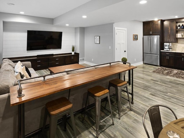 bar featuring high end refrigerator, baseboards, light wood finished floors, and recessed lighting