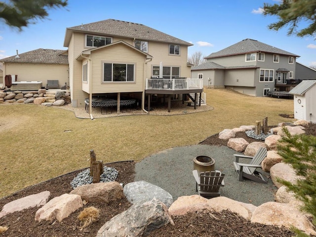 rear view of property featuring a lawn, a hot tub, an outdoor fire pit, and a deck