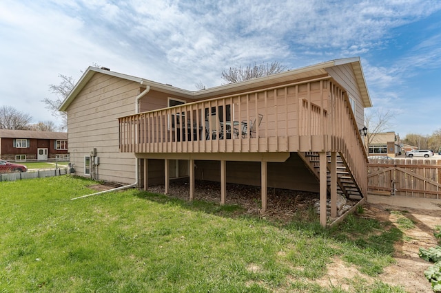 rear view of property with a yard, fence, a wooden deck, and stairs