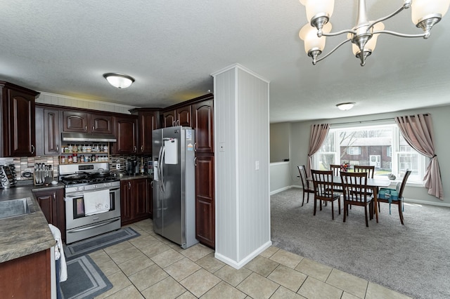 kitchen featuring dark countertops, appliances with stainless steel finishes, a notable chandelier, light carpet, and under cabinet range hood