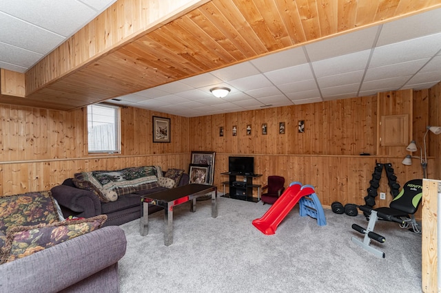 living room featuring carpet floors, wooden walls, and a drop ceiling