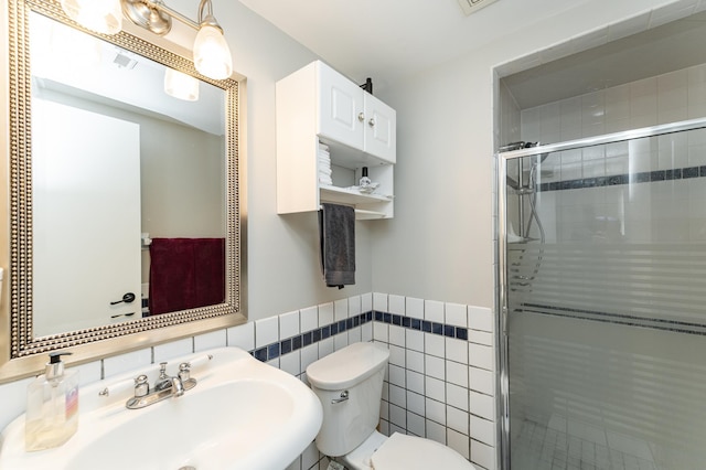 full bath featuring toilet, tile walls, a wainscoted wall, a sink, and a stall shower
