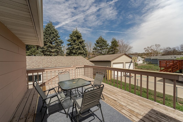 wooden terrace with a detached garage, a residential view, an outdoor structure, and outdoor dining space