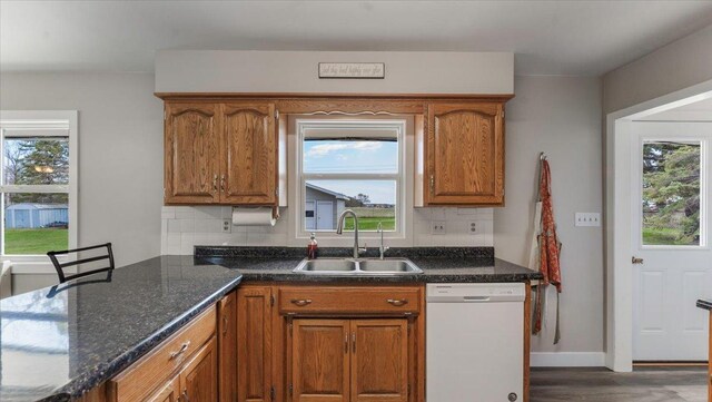 kitchen with a sink, dishwasher, brown cabinets, and tasteful backsplash