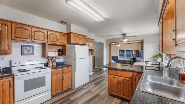 kitchen with ceiling fan, a sink, light wood finished floors, white appliances, and tasteful backsplash