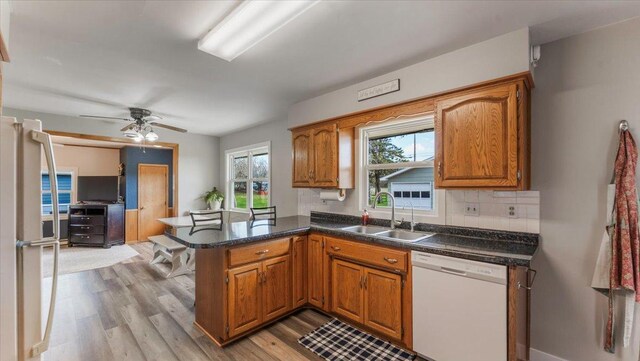 kitchen with brown cabinets, a peninsula, a sink, and dishwasher