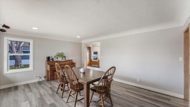 dining area with light wood-style floors, recessed lighting, a textured ceiling, and baseboards