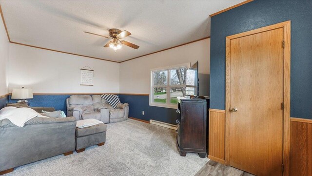 carpeted living room featuring crown molding, a ceiling fan, a wainscoted wall, and a baseboard radiator
