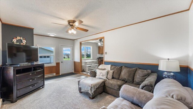 living area with crown molding, ceiling fan, baseboard heating, and a textured ceiling