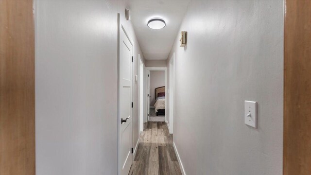 hall with baseboards and dark wood-style flooring
