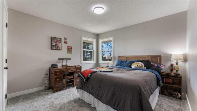 bedroom with a textured ceiling, light carpet, and baseboards