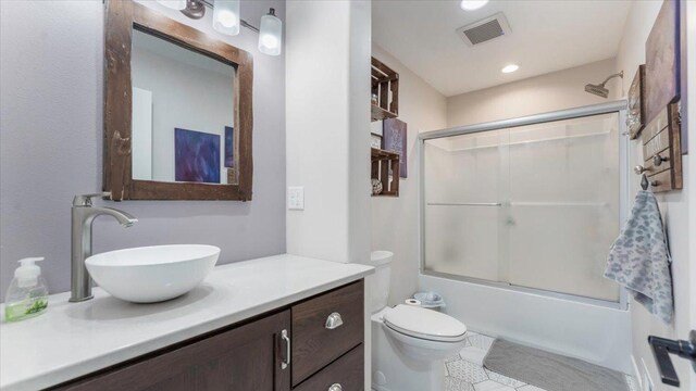 full bathroom featuring shower / bath combination with glass door, tile patterned flooring, vanity, toilet, and visible vents