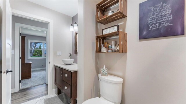 bathroom with vanity, baseboards, wood finished floors, and toilet