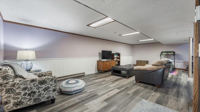 living area with wood finished floors, a textured ceiling, a wainscoted wall, and a baseboard radiator