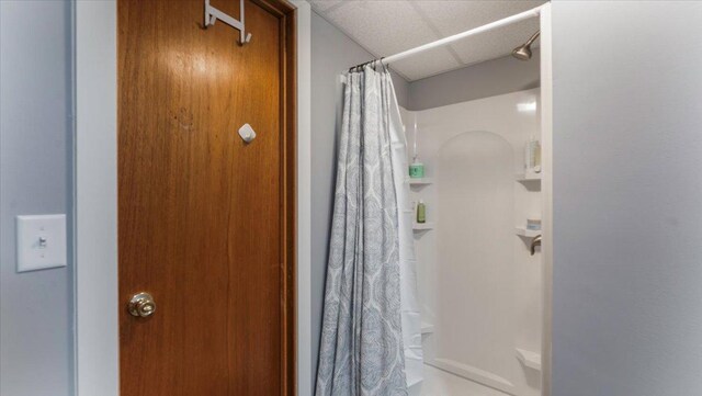full bath with a paneled ceiling and curtained shower