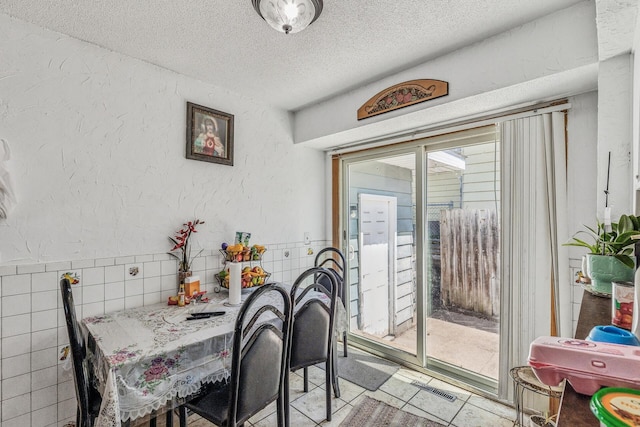 360 Hawthorne Ave E, Saint Paul, MN 55130 - dining area with tile walls, a textured ceiling, light tile patterned flooring, visible vents, and a textured wall