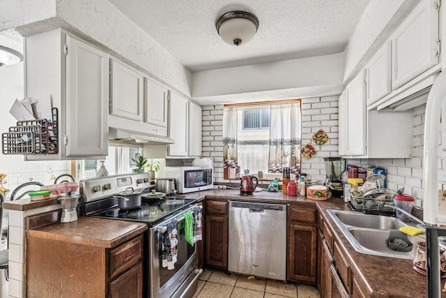 360 Hawthorne Ave E, Saint Paul, MN 55130 - kitchen featuring stainless steel appliances, a textured ceiling, under cabinet range hood, decorative backsplash, and dark countertops