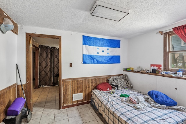 360 Hawthorne Ave E, Saint Paul, MN 55130 - bedroom featuring attic access, wooden walls, a textured ceiling, wainscoting, and light tile patterned floors