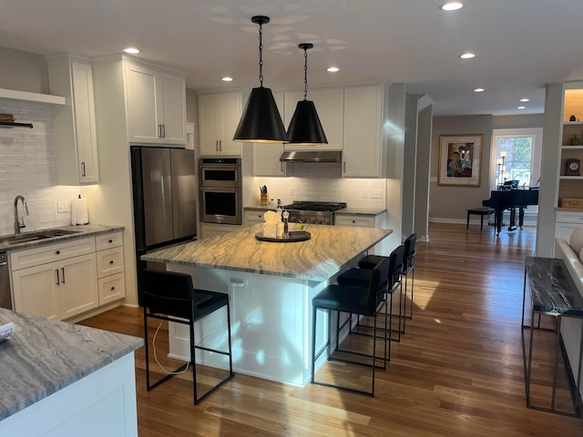 kitchen with a sink, stainless steel appliances, decorative backsplash, white cabinetry, and recessed lighting