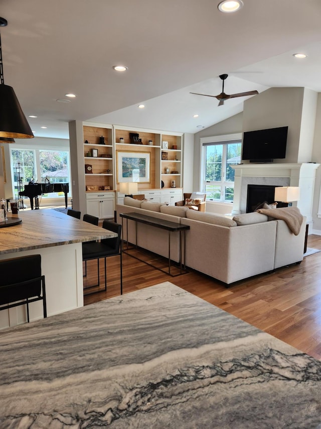 living room with healthy amount of natural light, wood finished floors, a fireplace, recessed lighting, and a ceiling fan