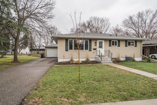 view of front of house with central AC, an outbuilding, a front yard, and a garage