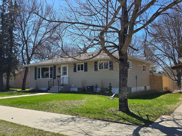 ranch-style home featuring fence, central AC, and a front lawn