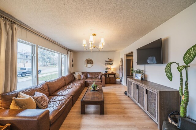 living room with light wood-type flooring, a textured ceiling, and a notable chandelier