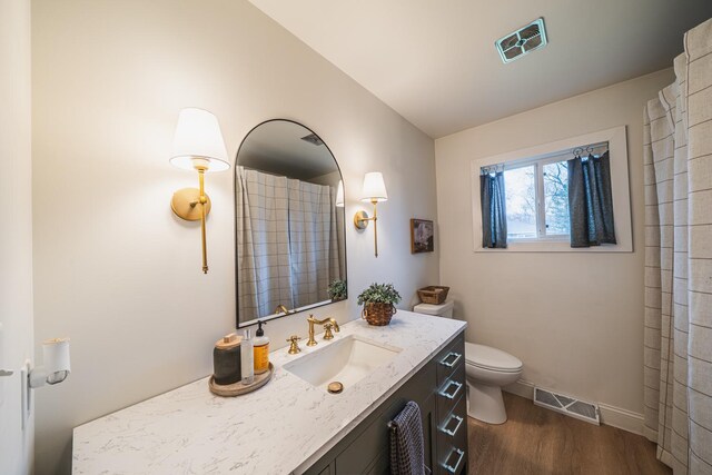 bathroom with visible vents, baseboards, wood finished floors, and toilet