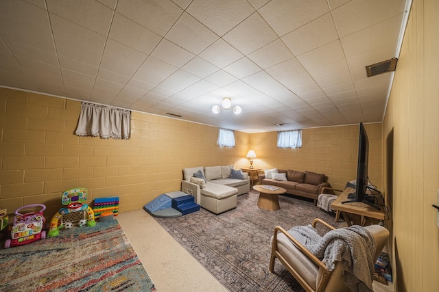 living room with visible vents and concrete block wall